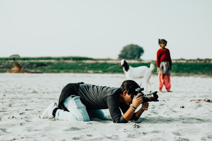 a man laying in the sand with a camera